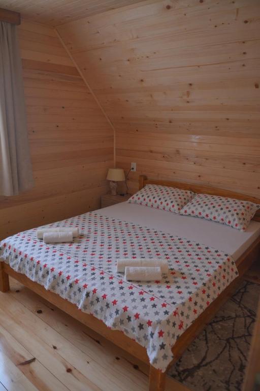 uma cama num quarto de madeira com duas toalhas em Dobar pogled em Bajina Bašta