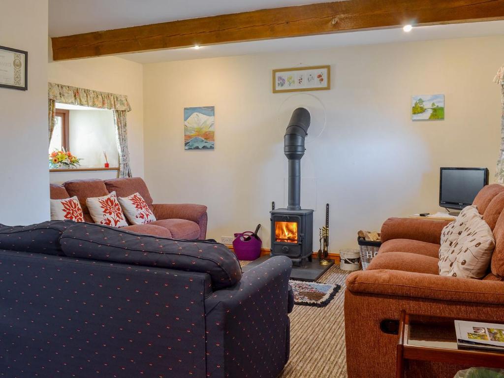 a living room with a couch and a wood stove at Stonefold Cottage in Waberthwaite