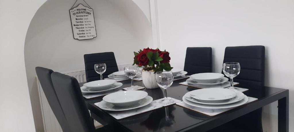 a black dining room table with plates and wine glasses at Stylish and homey 3 bedroom house with free parking & Wi-Fi in Minworth