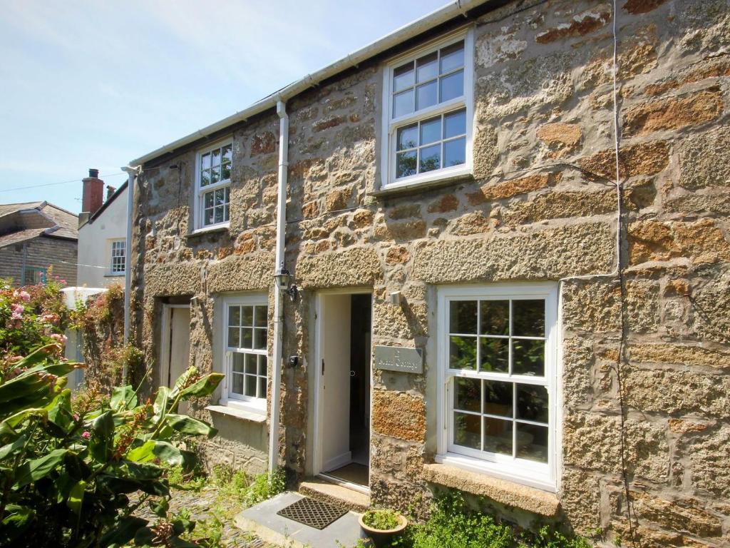 an old stone house with white windows and a door at Bucca Cottage in Newlyn