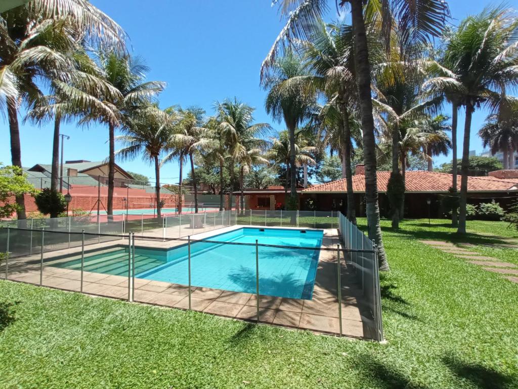 a swimming pool with a fence around it with palm trees at BauHouse Asuncion in Asunción