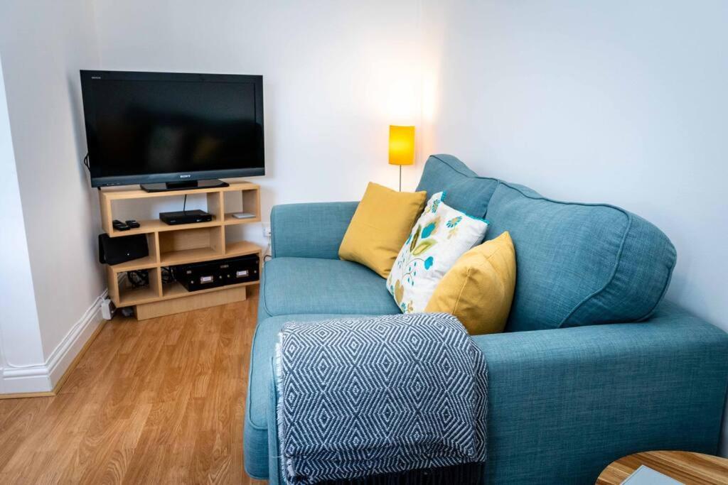 a living room with a blue couch and a flat screen tv at Charming 1-bed Southside Flat in Great Location in Kings Park
