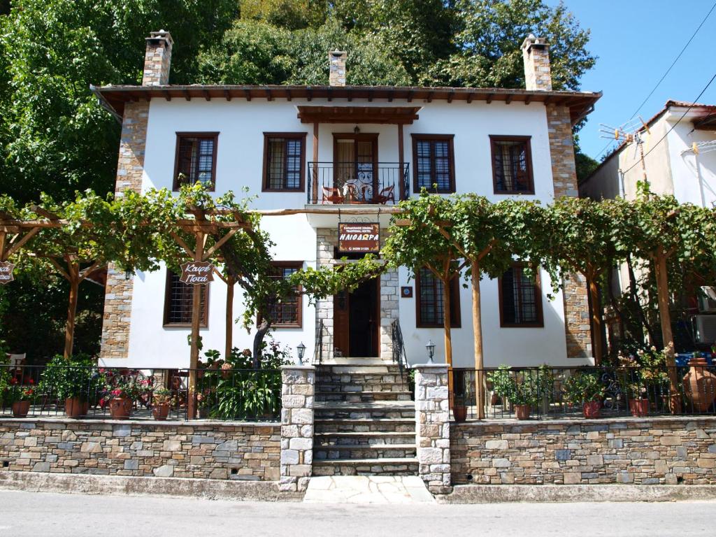 dom z kamienną ścianą i drzewami w obiekcie Heliodora w mieście Kissos