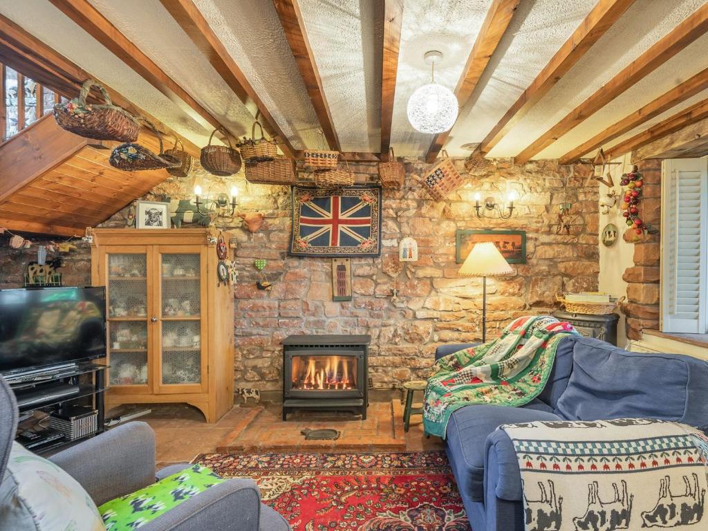 sala de estar con pared de piedra y chimenea en The Cowshed, en Penrith