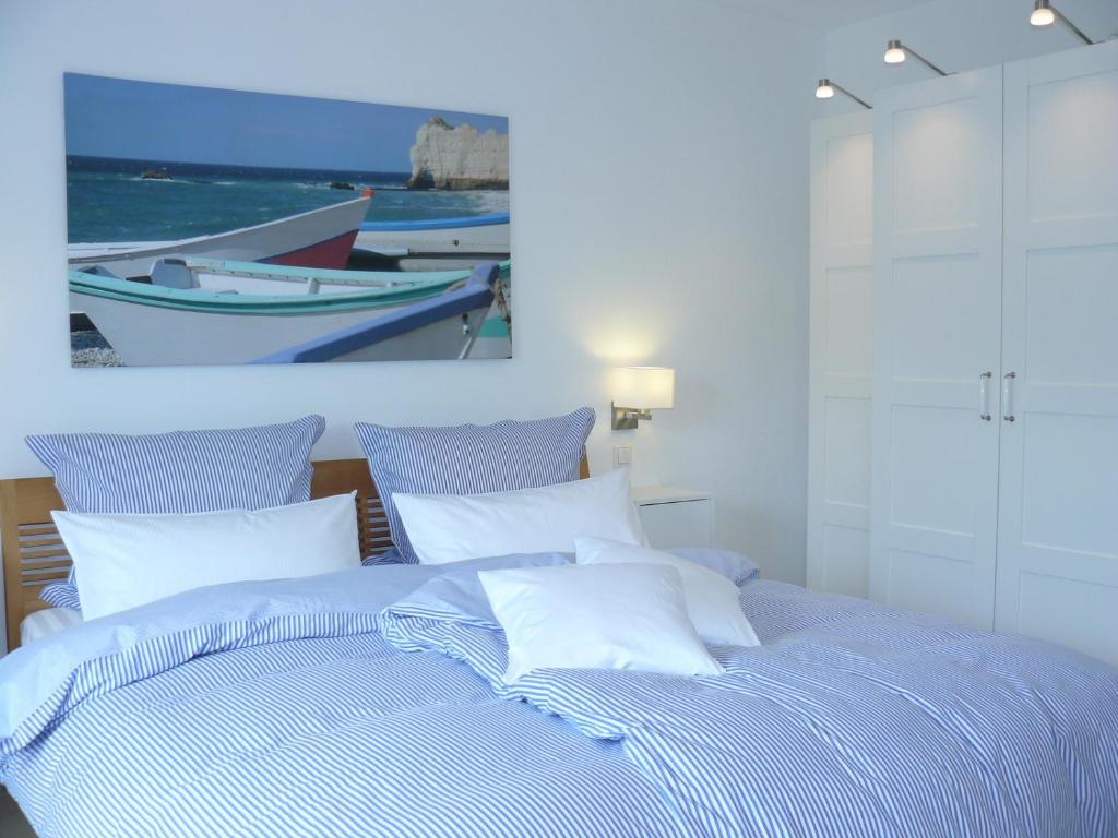 1 cama azul con almohadas blancas y una pintura en la pared en Gästehaus Ina-Maria, Apartments, en Obernhof