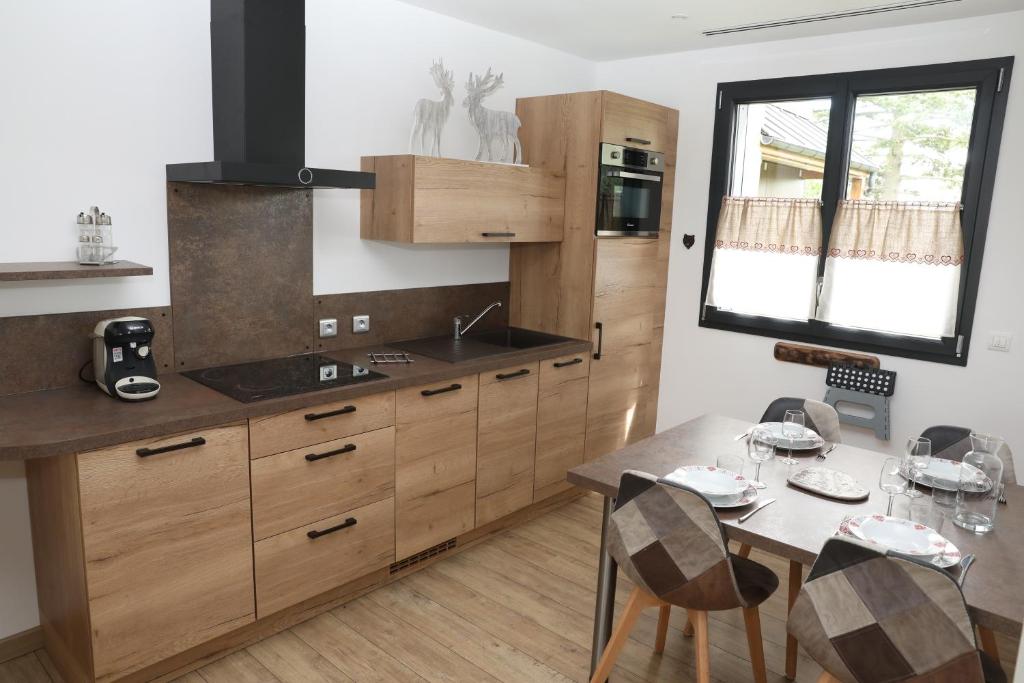 una cocina con armarios de madera y una mesa con sillas. en Les Chalets du Bois Blanc, 