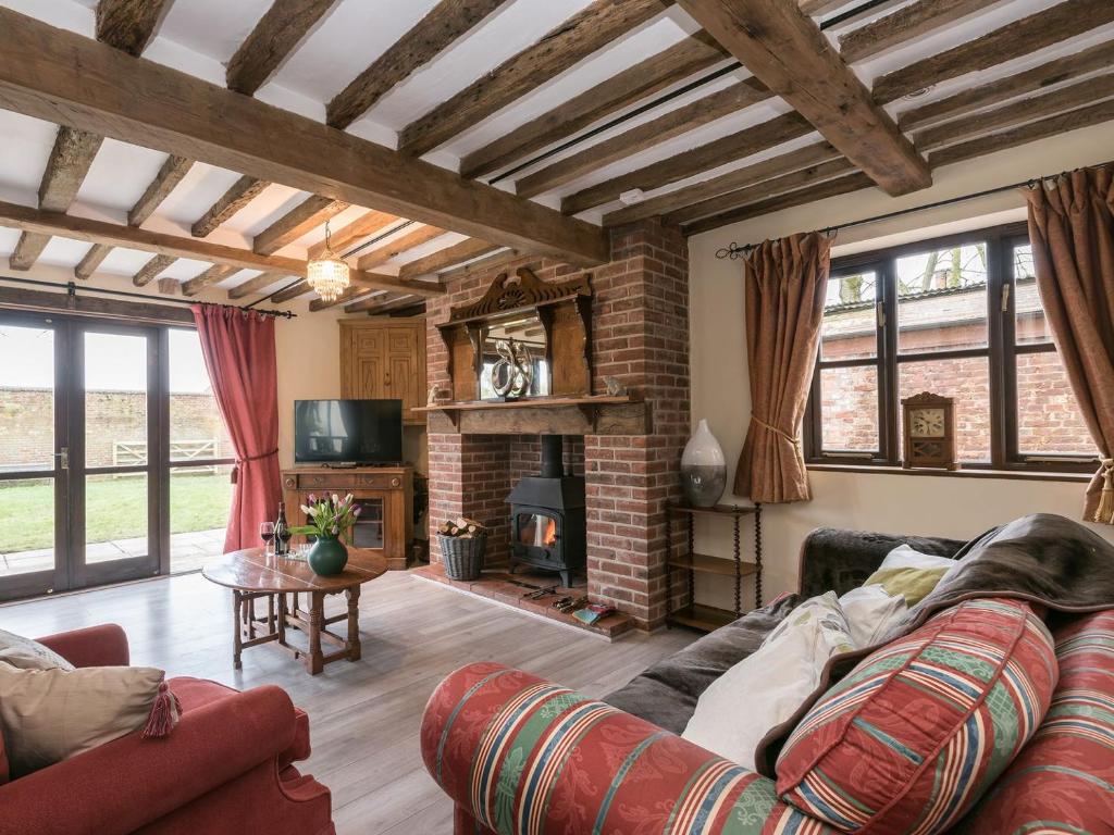 a living room with a couch and a fireplace at The Old Hall Coach House in Ashwellthorpe