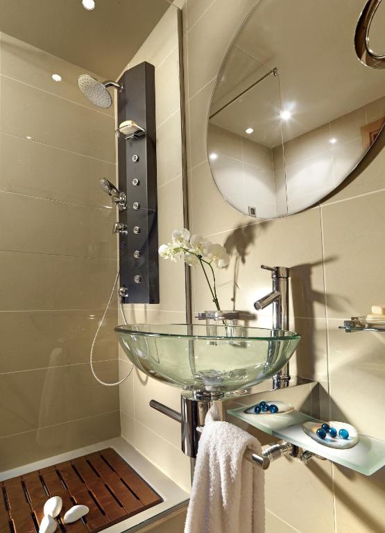 a bathroom with a glass sink and a mirror at Out Of The Blue Resort & Spa in Agia Pelagia