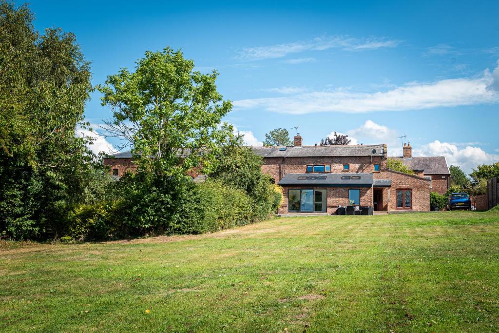 a brick house with a large yard in front of it at No1 Little Barrow Barns - Sleeps 10 in Chester