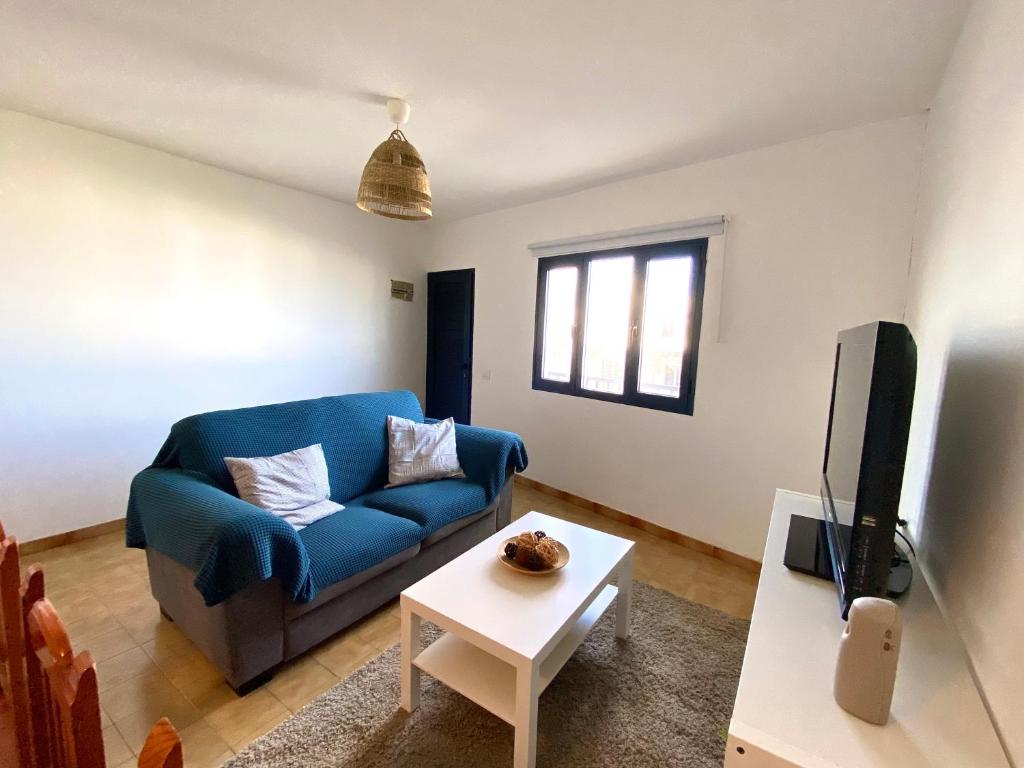 een woonkamer met een blauwe bank en een tv bij La Santa Azul in La Santa