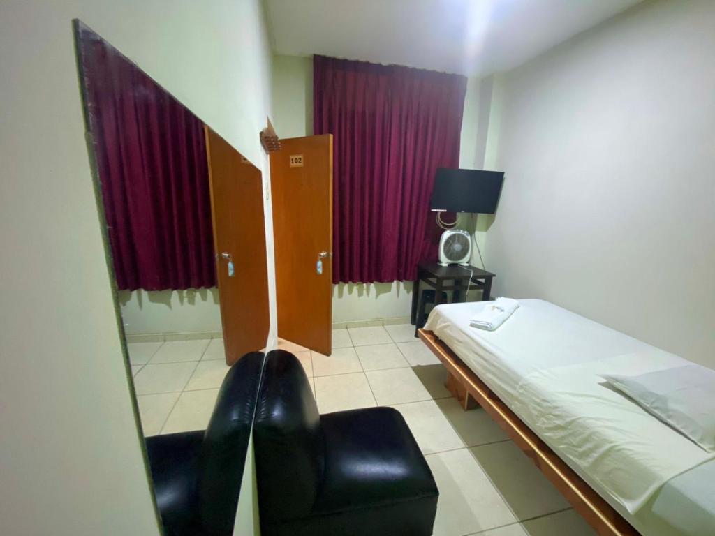 een kamer met een bed en een stoel. bij HOSTAL BULEVAR in Piura