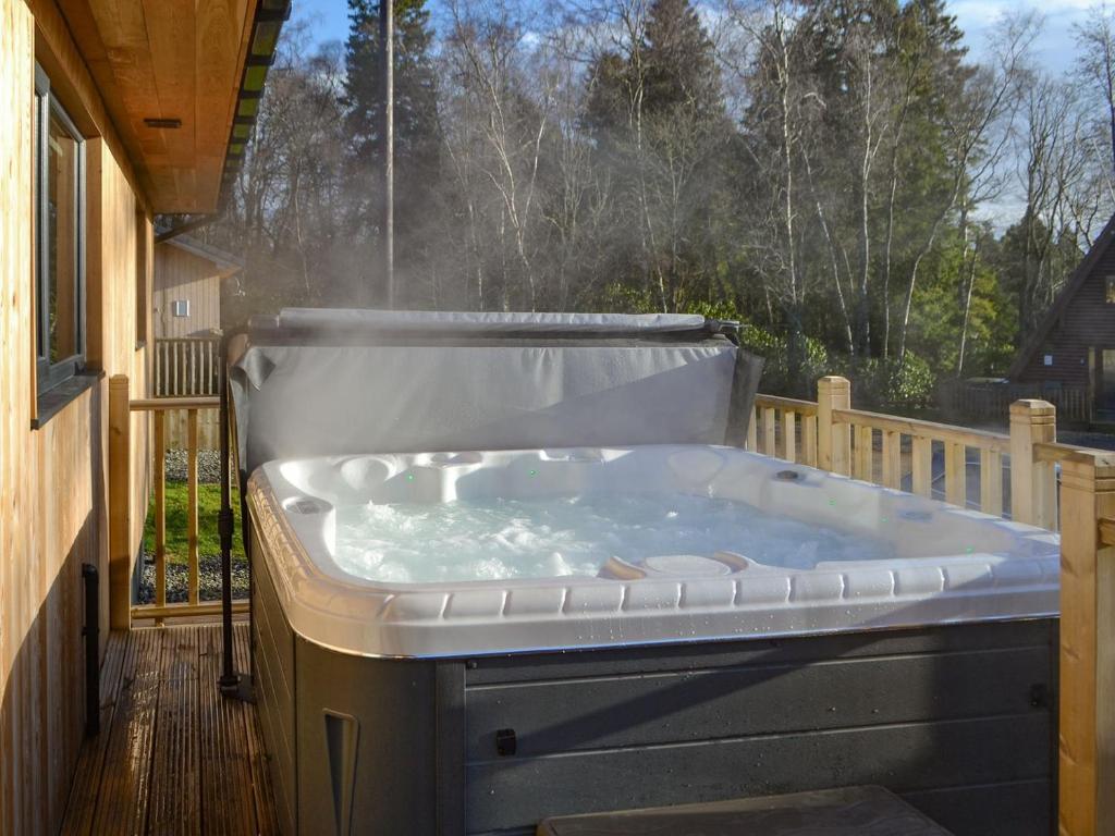 a hot tub sitting on a deck with a window at Juniper Lodge - UKC3931 in Otterburn