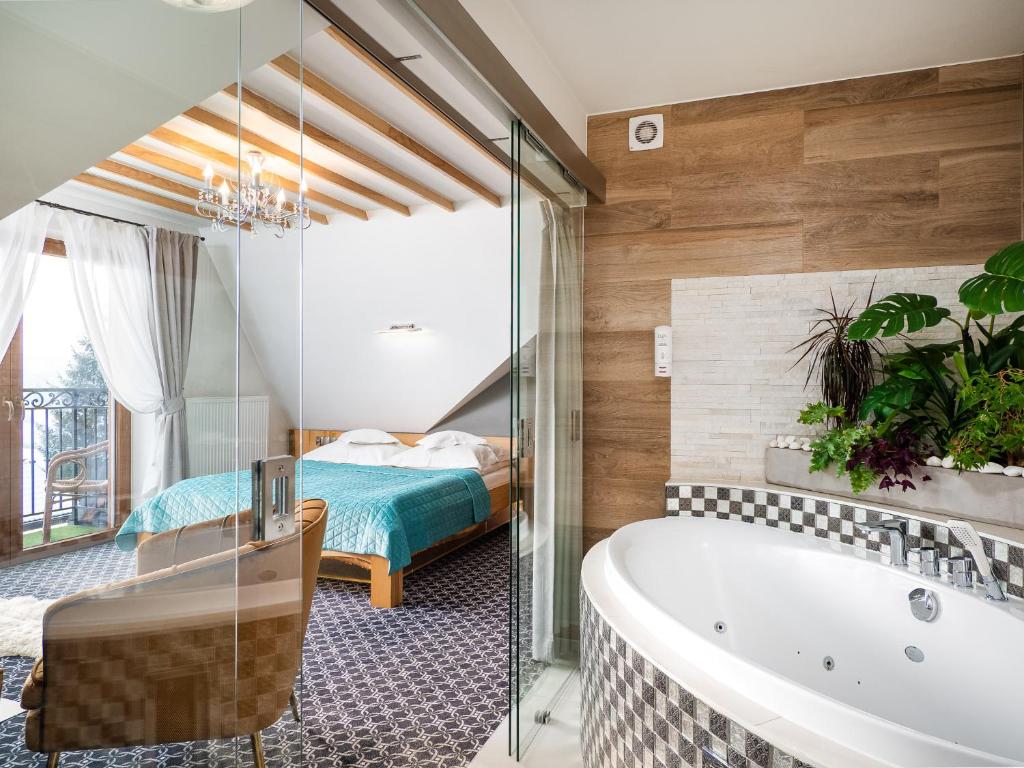 a bathroom with a tub and a bedroom at ECO Villa Grand Karpatia Ski&Spa in Murzasichle