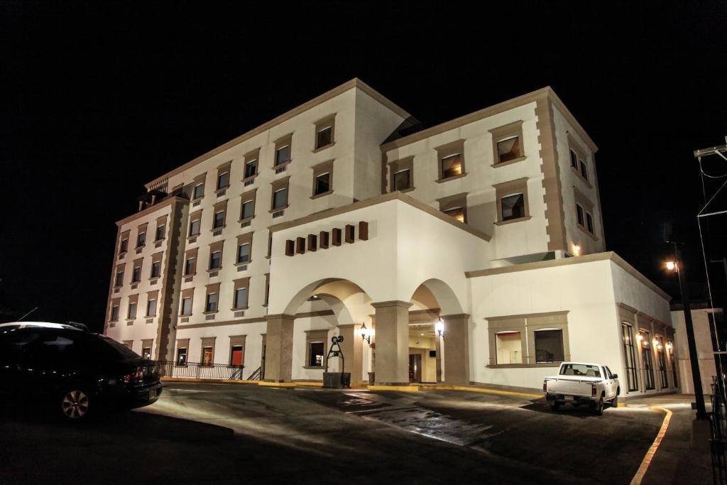 a white building with a car parked in front of it at Hotel La Mina Parral in Hidalgo del Parral