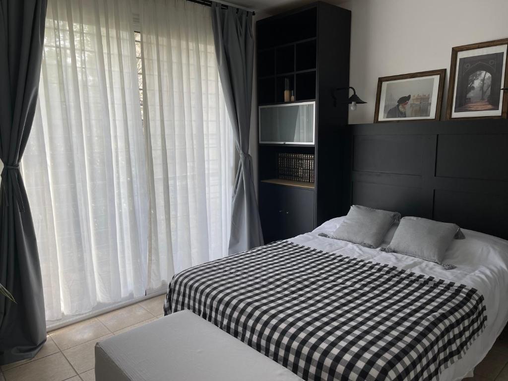 1 dormitorio con 1 cama con manta blanca y negra en Estudio en Belén de Escobar