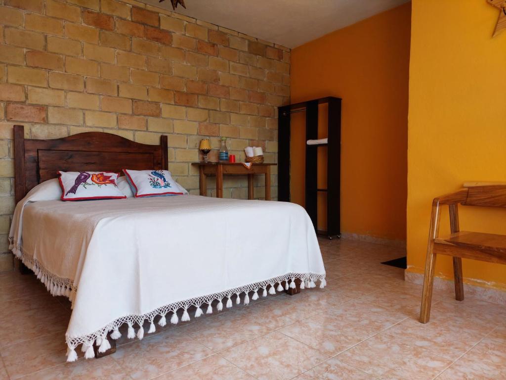 1 dormitorio con cama y pared de ladrillo en Casa Cejota en Huautla de Jiménez