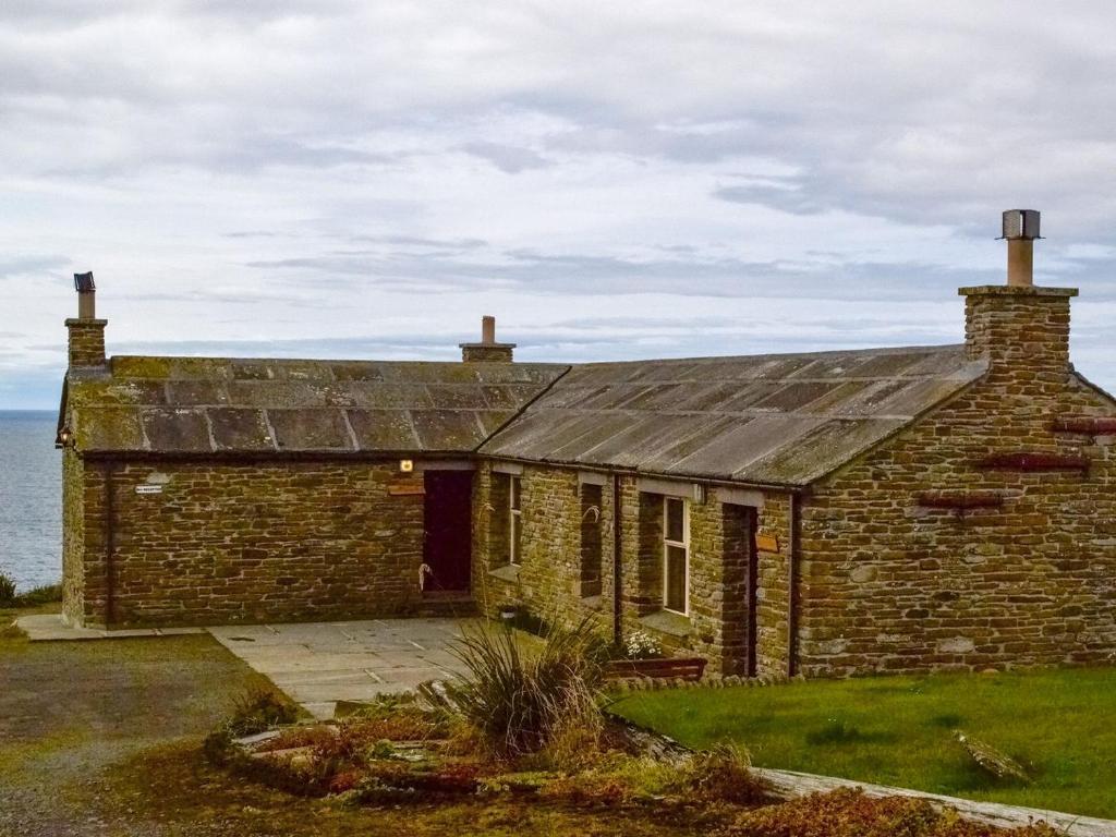 an old brick house with the ocean in the background at Three Island View - W42427 in Pierowall