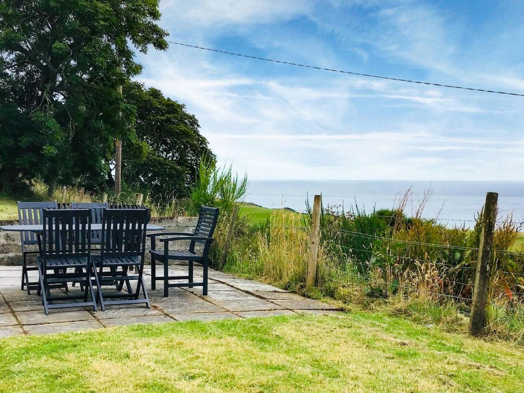 two chairs and a table with the ocean in the background at Owl Cottage in Kilmote