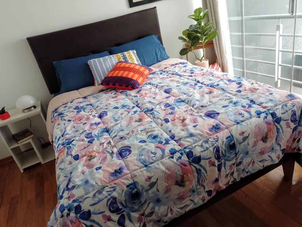 a bed with a colorful comforter on it in a bedroom at En el centro y hermosa vista! Con cochera in Trujillo