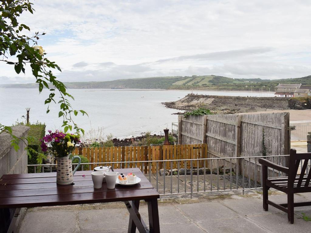 a wooden table sitting on a balcony with a view of the water at Seadrift in New Quay