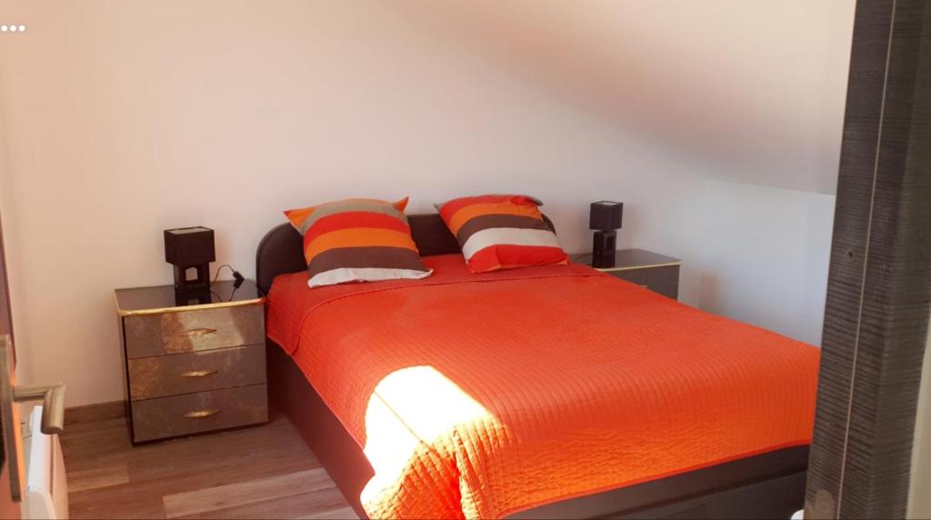 a bedroom with a bed with orange sheets and pillows at Chez Monique in Maubert-Fontaine