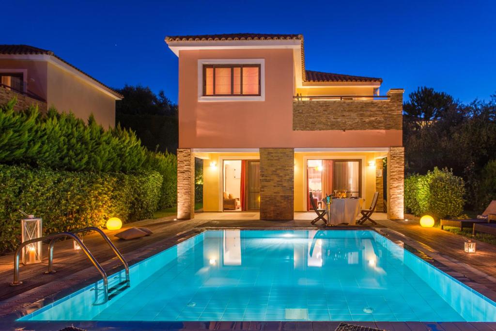 a villa with a swimming pool in front of a house at Hotel St John Villas in Tsilivi