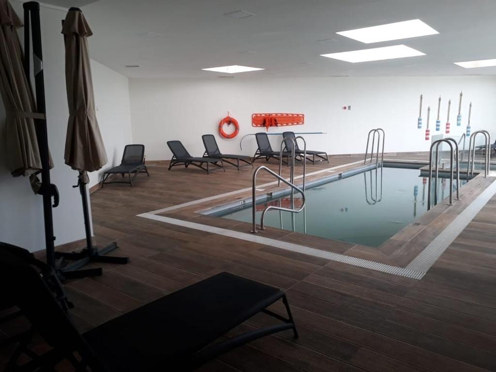 a swimming pool in a room with chairs around it at Departamento en Costa de Montemar in Concón