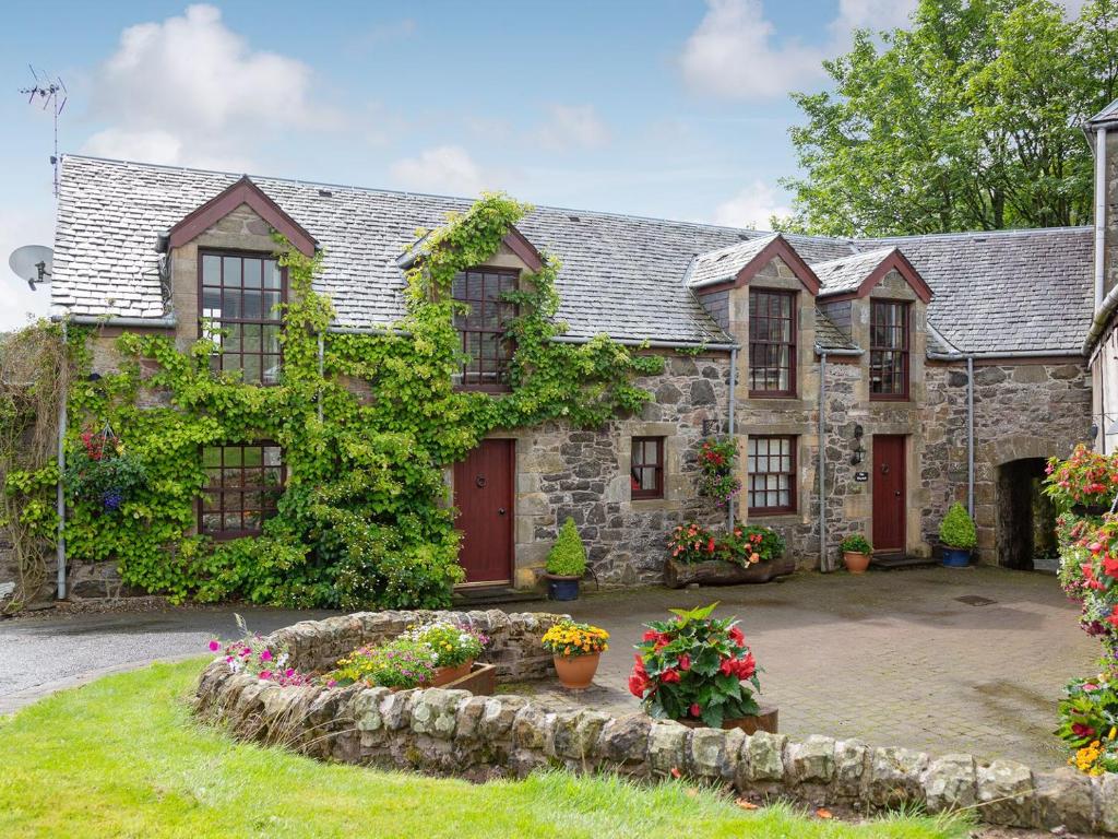 MilnathortにあるThe Hayloftの赤い扉と庭のある古い石造りの家