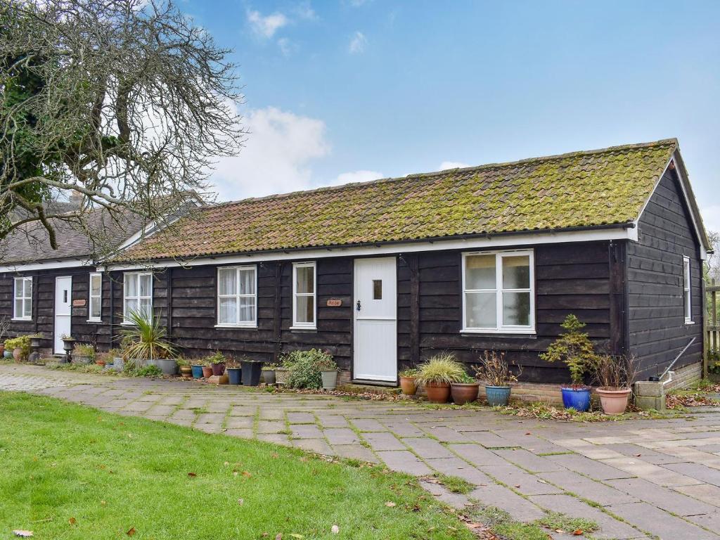 a wooden house with a white door and some plants at Rose Cottage - W41462 in Sturminster Newton