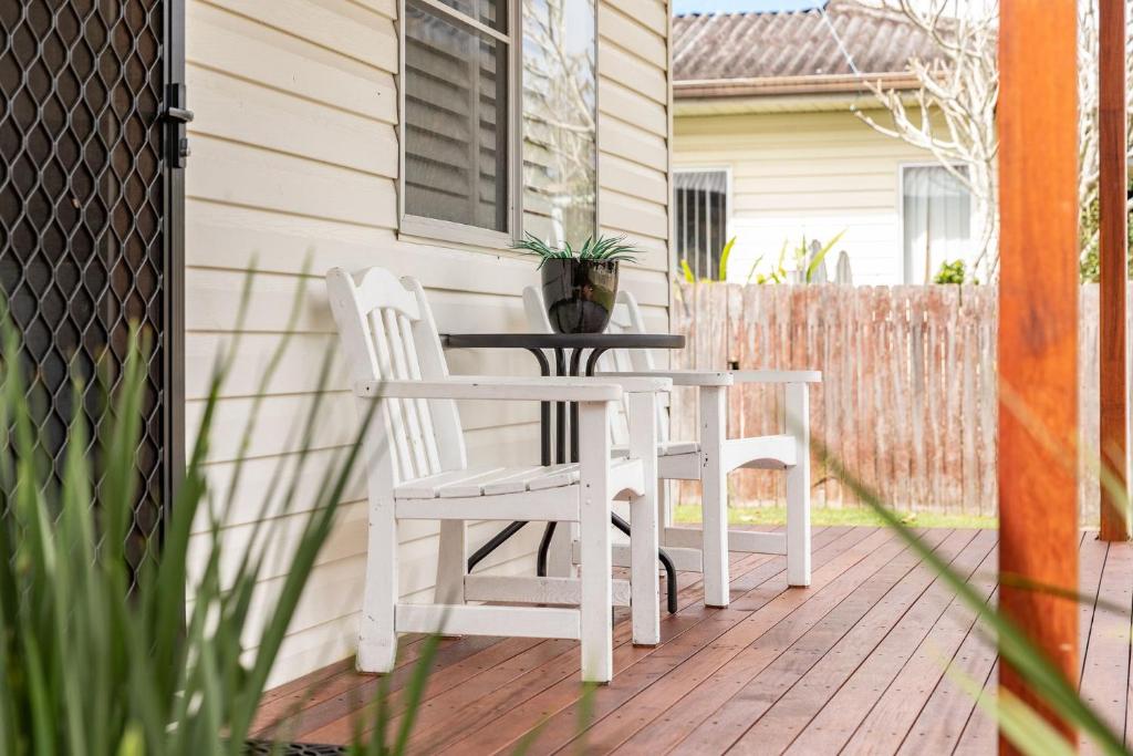 two white chairs and a table on a patio at Cottage on Bruce in Forster