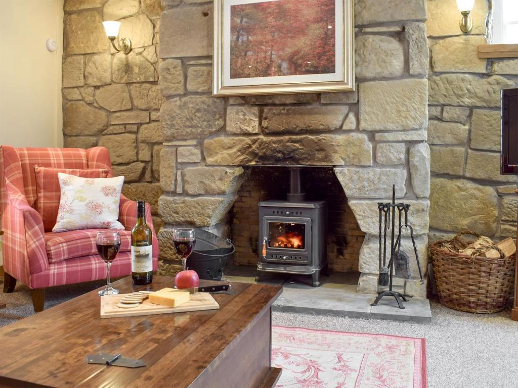 a living room with a stone fireplace and a table with wine glasses at Deuchars Cottage in Kenmore