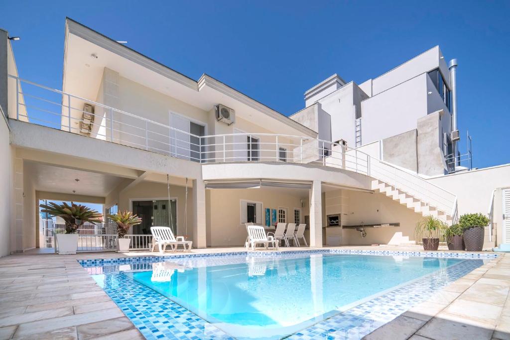 une villa avec une piscine en face d'une maison dans l'établissement Casa de Praia em Bombinhas Beach House, à Bombinhas