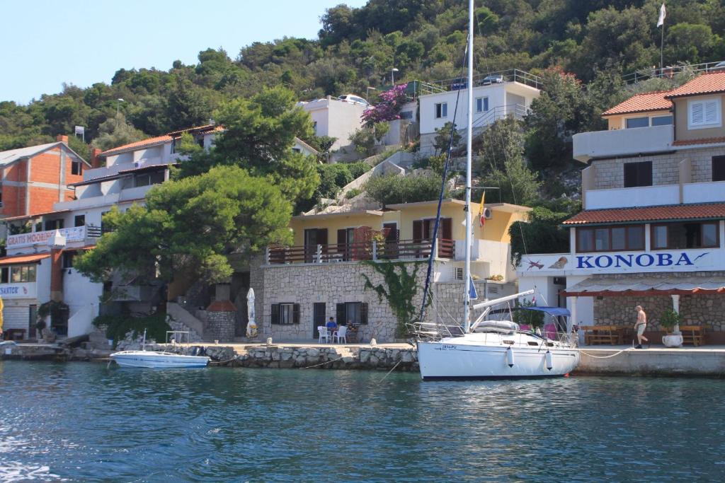una barca a vela è ormeggiata nell'acqua accanto agli edifici di Apartments by the sea Zaklopatica, Lastovo - 8347 a Lastovo