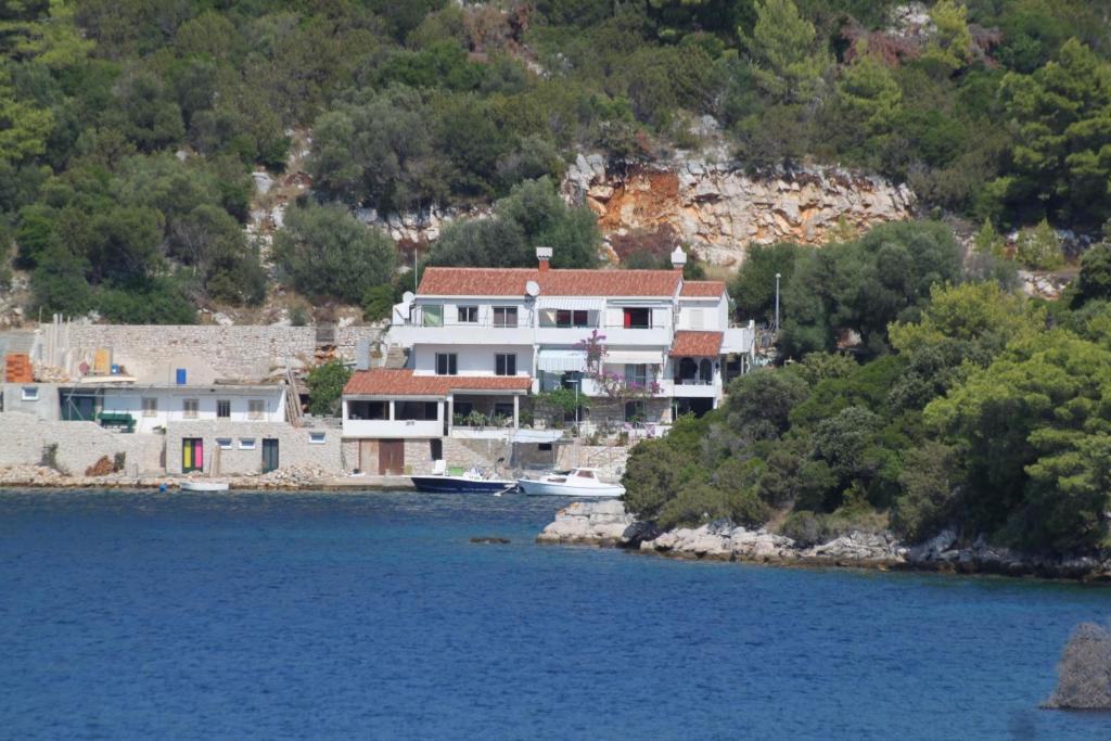 une grande maison assise sur le côté d'une masse d'eau dans l'établissement Apartments by the sea Pasadur, Lastovo - 8391, à Lastovo