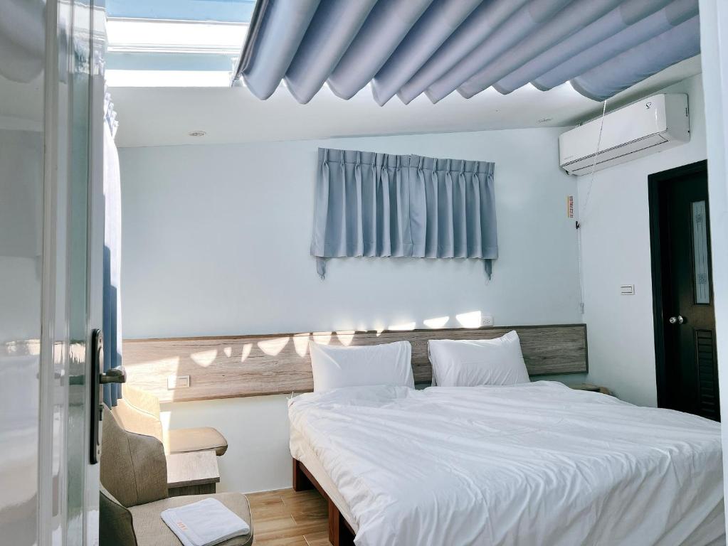 馬公市的住宿－月裡民宿，一间卧室配有一张带白色床单的大床