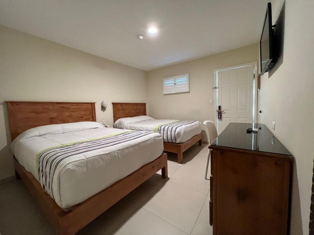 a bedroom with two beds and a television in it at Hotel Baja in Tijuana