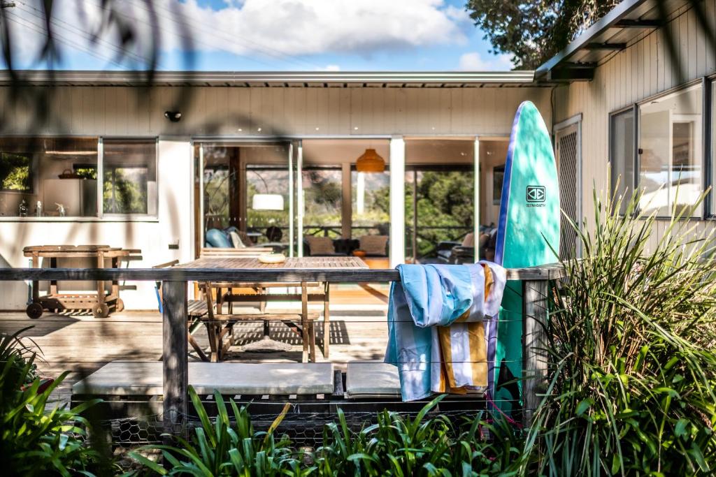 a patio with a table and a surfboard on a house at Le Shack - Freycinet Holiday Houses in Coles Bay