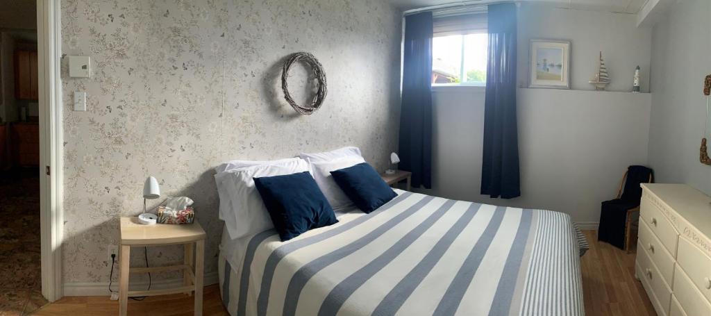 a bedroom with a bed with blue and white stripes at Aux quatre vents 3,5 logement intime et privé in Lac-Mégantic
