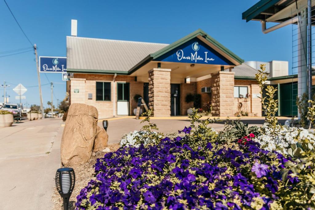 a building with purple flowers in front of it at Oasis Motor Inn Blackall in Blackall