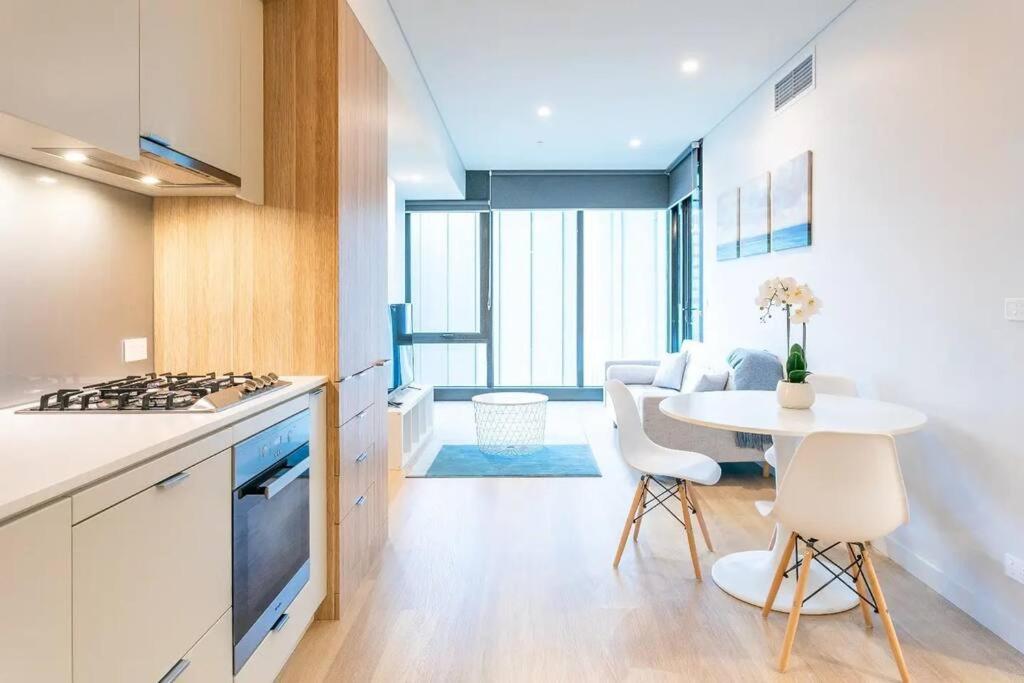 a kitchen with a table and a kitchen with a stove at Lovely One Bedroom + Study with Infinity Pool in Sydney