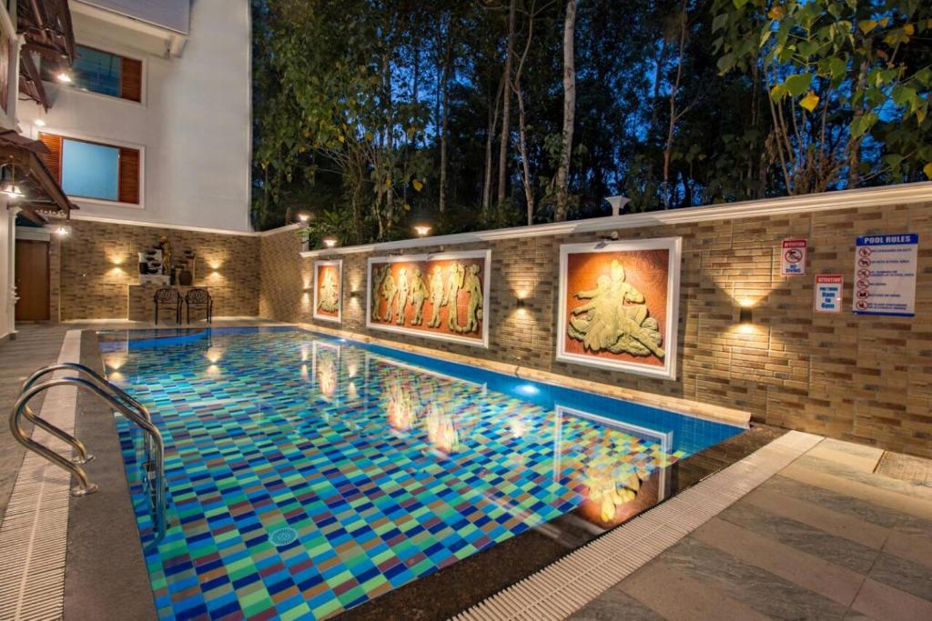 a large swimming pool with blue tiles on a wall at Crown Valley Thekkady in Thekkady