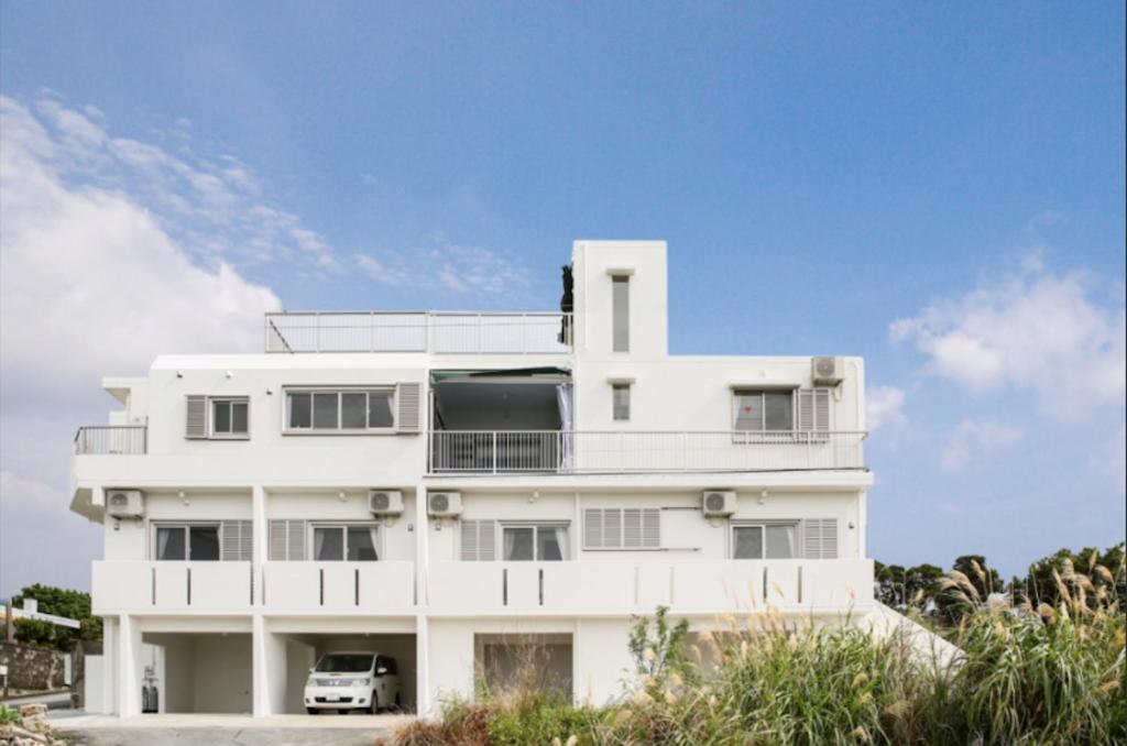 un edificio blanco con un coche aparcado delante de él en Itoman - House / Vacation STAY 7483, en Itoman