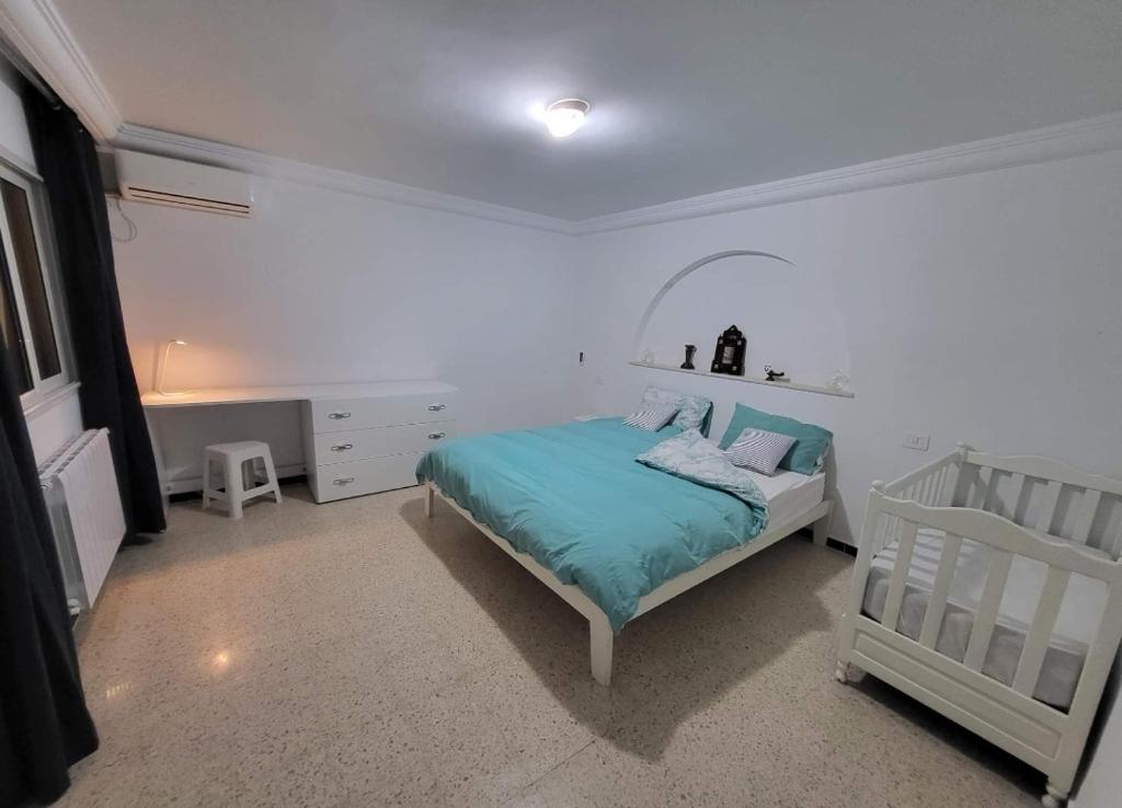 a white bedroom with a bed and a crib at Écrin in Sousse