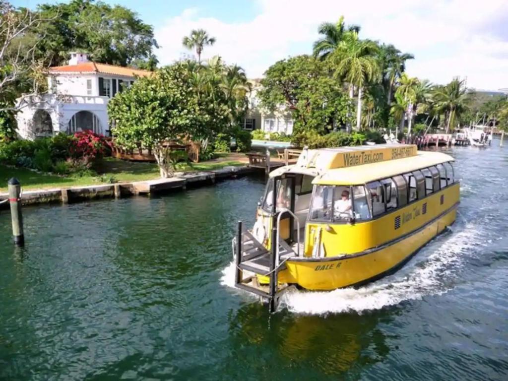 a yellow boat in the water near a house at Private Hollywood APT Near Beach Airport & Casino in Hollywood