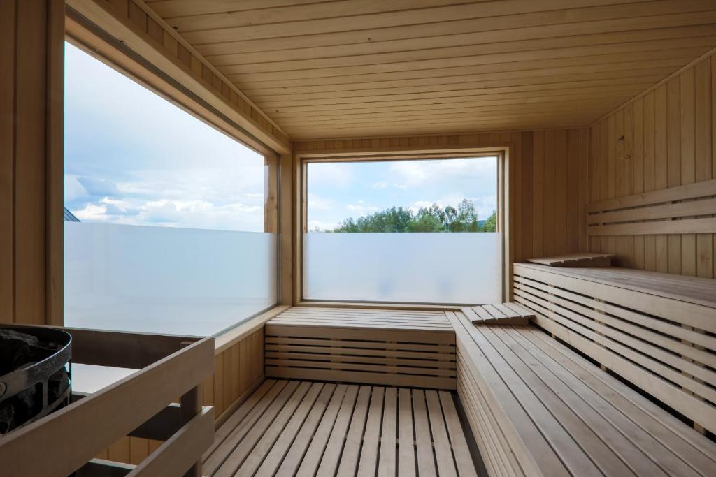 Bright wooden sauna with tiered benches, frosted windows, and view of trees outside.
