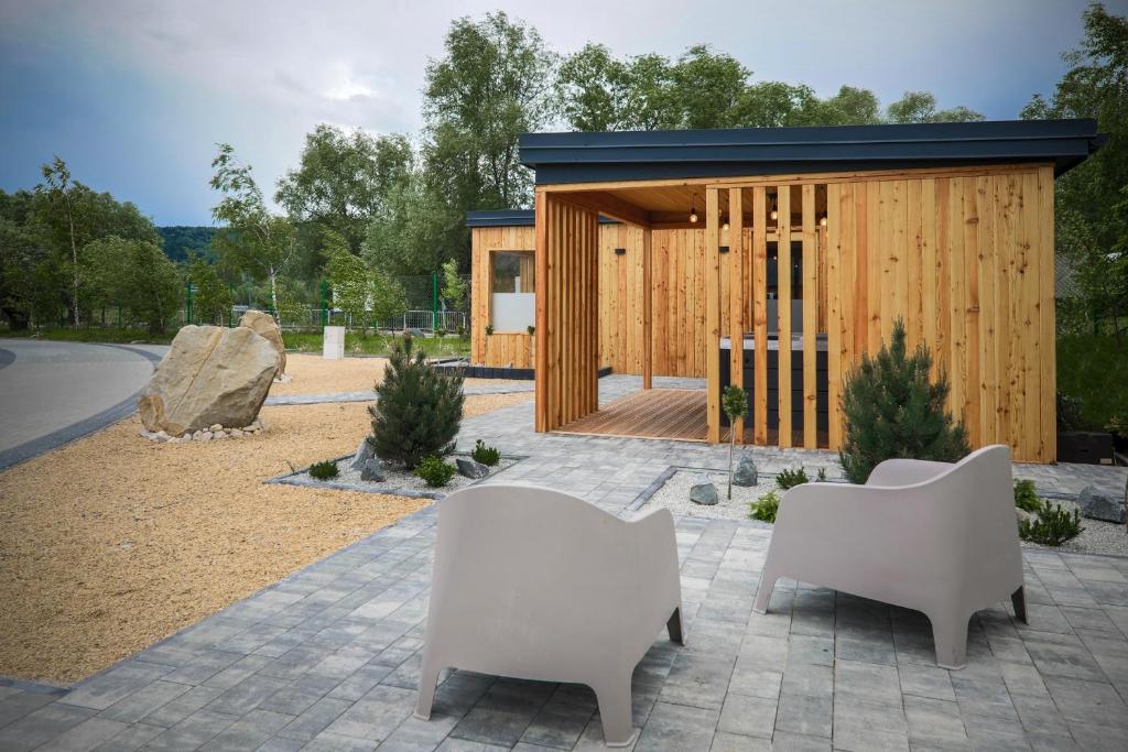 Contemporary wooden cabin exterior with open porch, patio chairs, and small landscaped garden.