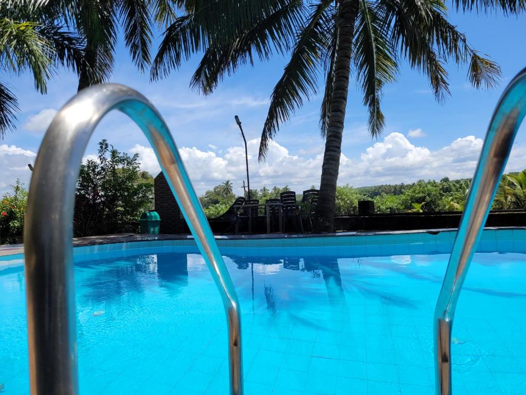 una piscina con palmeras en el fondo en Homes Stay In Candolim GOA, en Marmagao