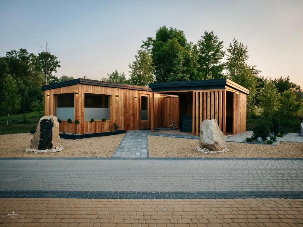 Low wooden cabins with paved walkway, gravel landscaping, and surrounding trees at dusk.