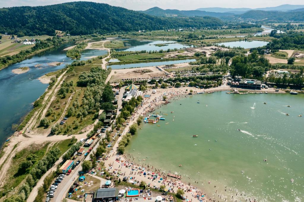 Aerial view of busy lakeside beach with crowds, water activities, and surrounding green hills.