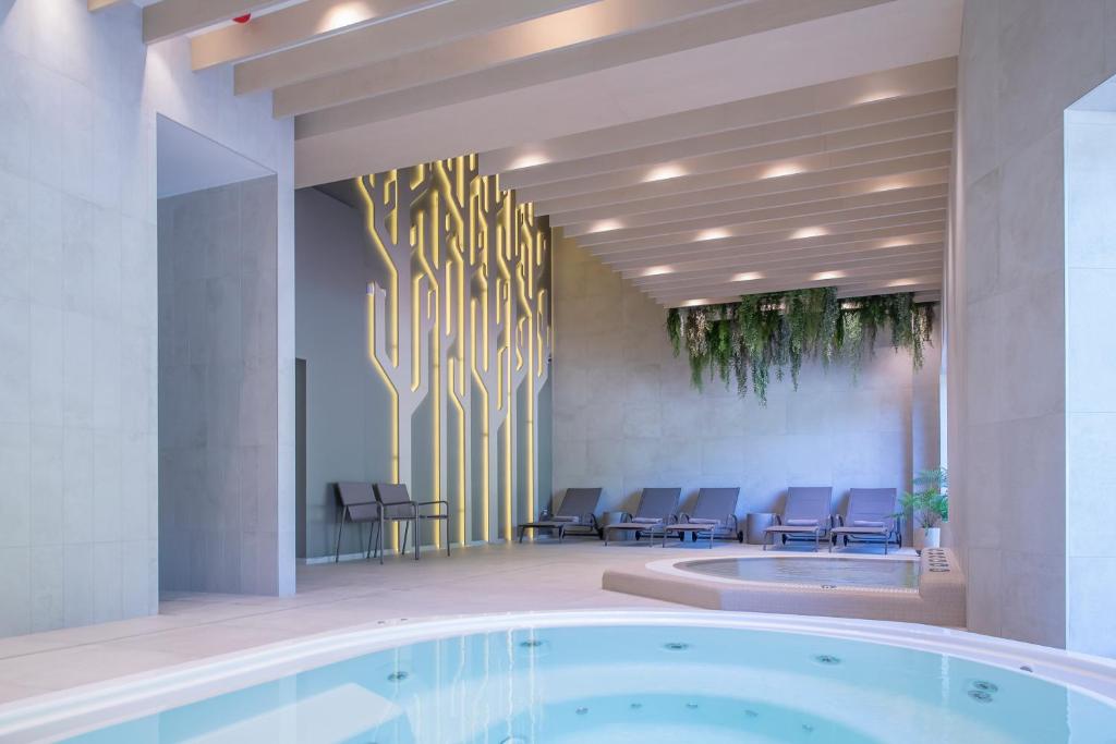a large lobby with a hot tub and chairs at Nykščio Namai & SPA in Anykščiai